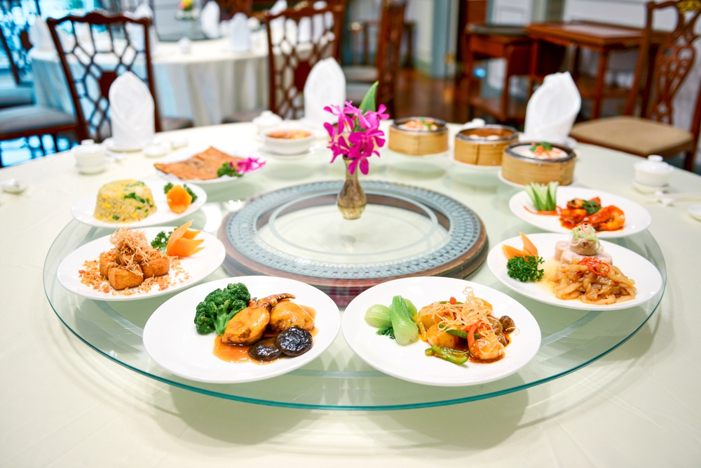 อาหารจีนหลายเมนูบนโต๊ะทรงกลมในร้านอาหาร